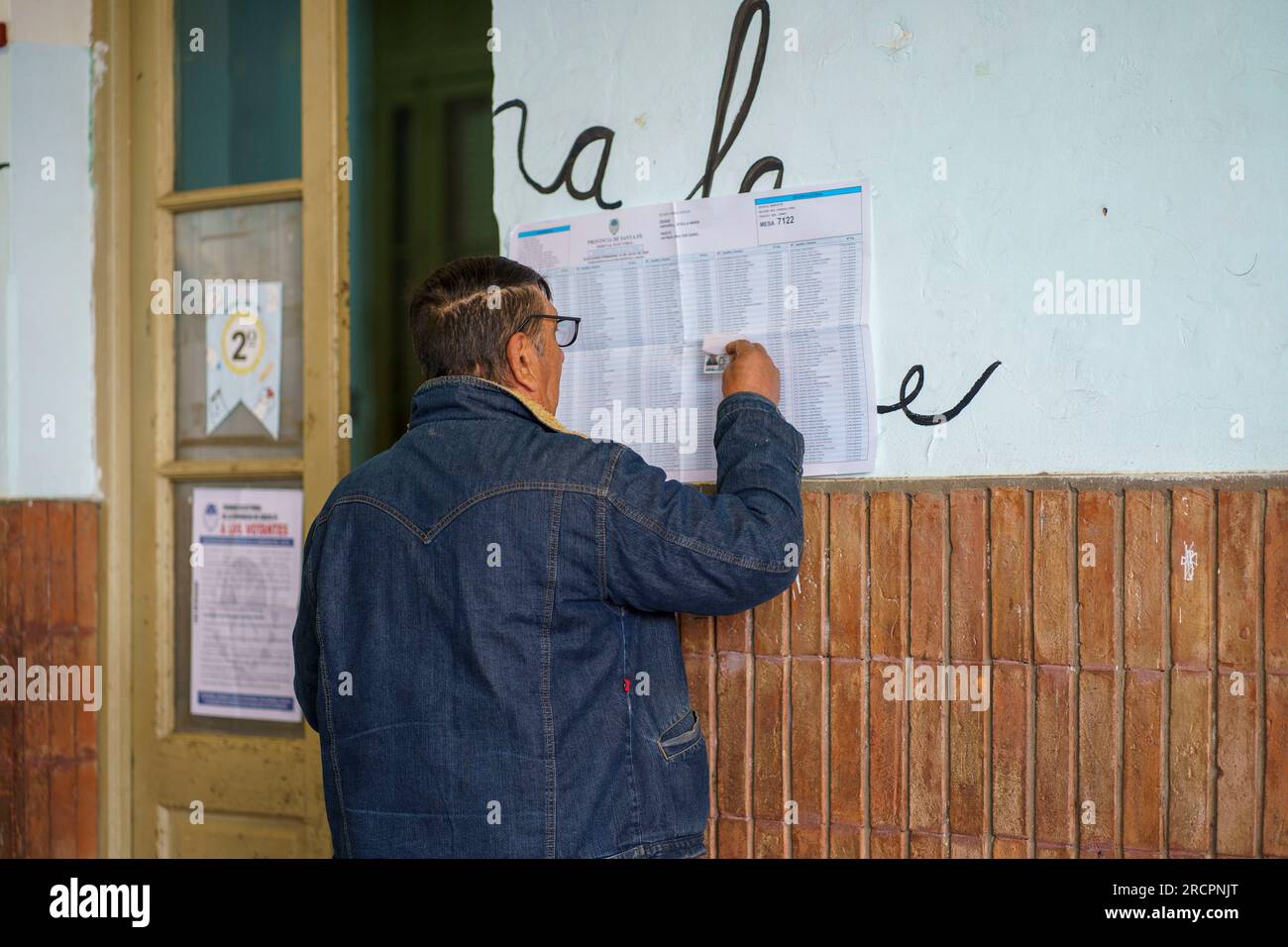 A man checks his name on an electoral roll at a polling station in Firmat, Santa Fe at the beginning of the primary elections (PASO). This election is seen as a major test for the opposing coalition Juntos por el Cambio, with Presidential candidates Horacio Rodriguez Larreta and Patricia Bullrich supporting two candidates for Governor, Maximiliano Pullaro and Carolina Losada respectively, that have engaged in a battle that escalated to the point of accusing Pullaro of complicity with drug dealers when he was Ministry of Security.Citizens in the Province of Santa fe will have to vote no less th Stock Photo