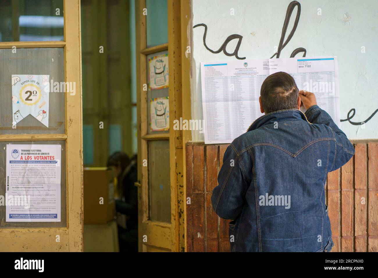 A man checks his name on an electoral roll at a polling station in Firmat, Santa Fe at the beginning of the primary elections (PASO). This election is seen as a major test for the opposing coalition Juntos por el Cambio, with Presidential candidates Horacio Rodriguez Larreta and Patricia Bullrich supporting two candidates for Governor, Maximiliano Pullaro and Carolina Losada respectively, that have engaged in a battle that escalated to the point of accusing Pullaro of complicity with drug dealers when he was Ministry of Security.Citizens in the Province of Santa fe will have to vote no less th Stock Photo