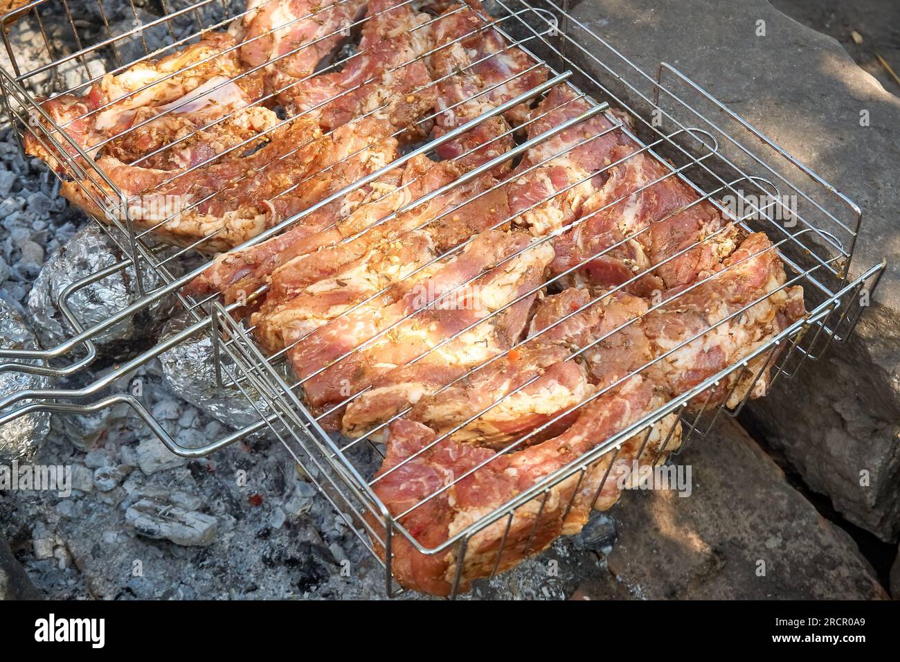 Cooking pork ribs in a charcoal grill at a picnic in the countryside