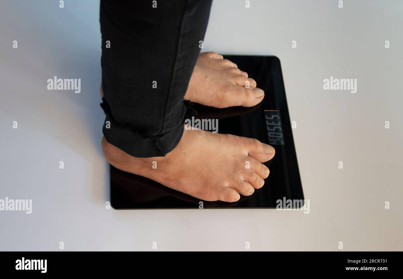 standing on the indoor scales There is space for text. The problem of being overweight or underweight Stock Photo