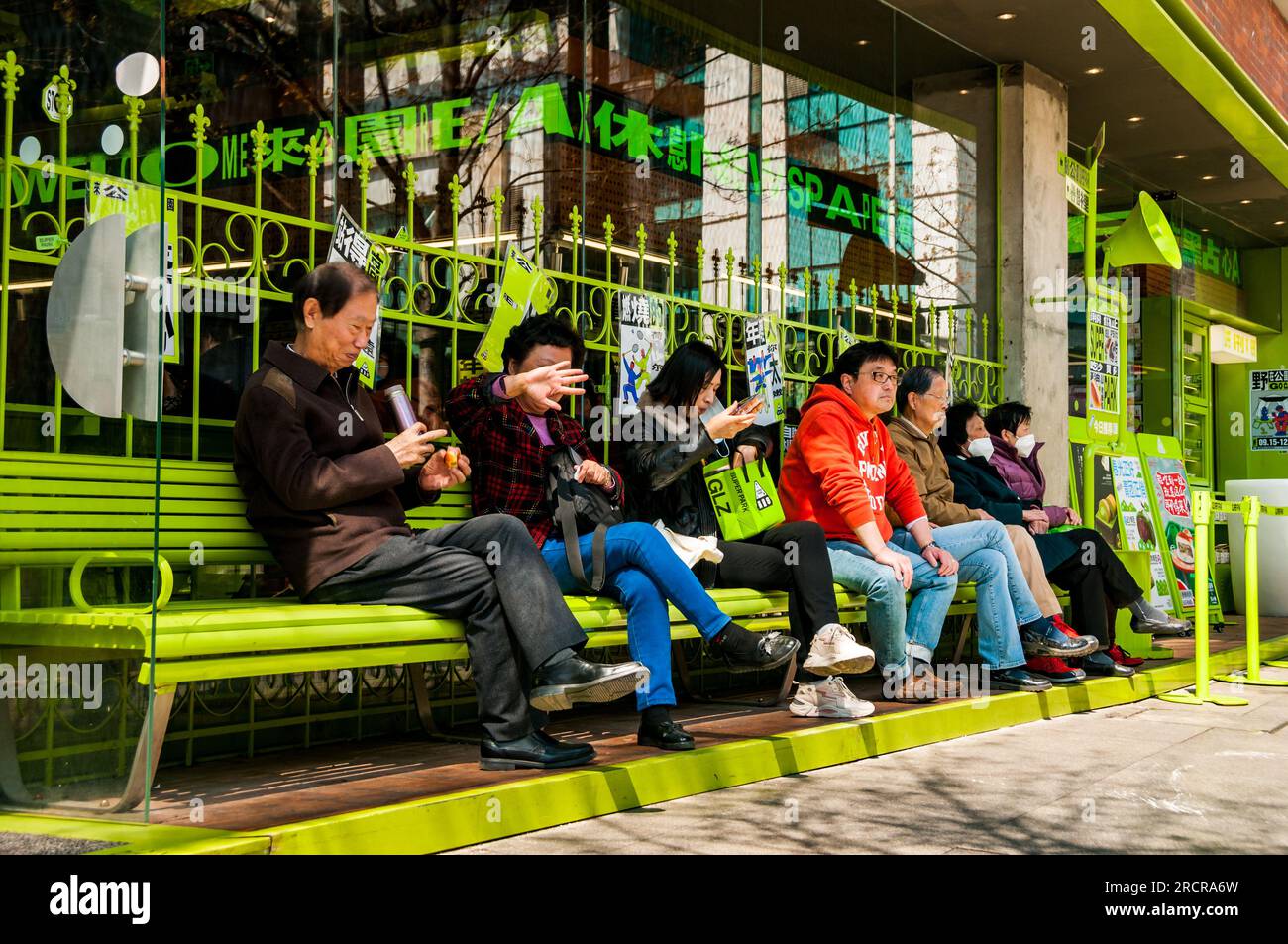 People sitting on the benches outside the Super Park bakery store on the Maoming North Street in central Shanghai. Feng Sheng Li, Jing’an District, Sh Stock Photo