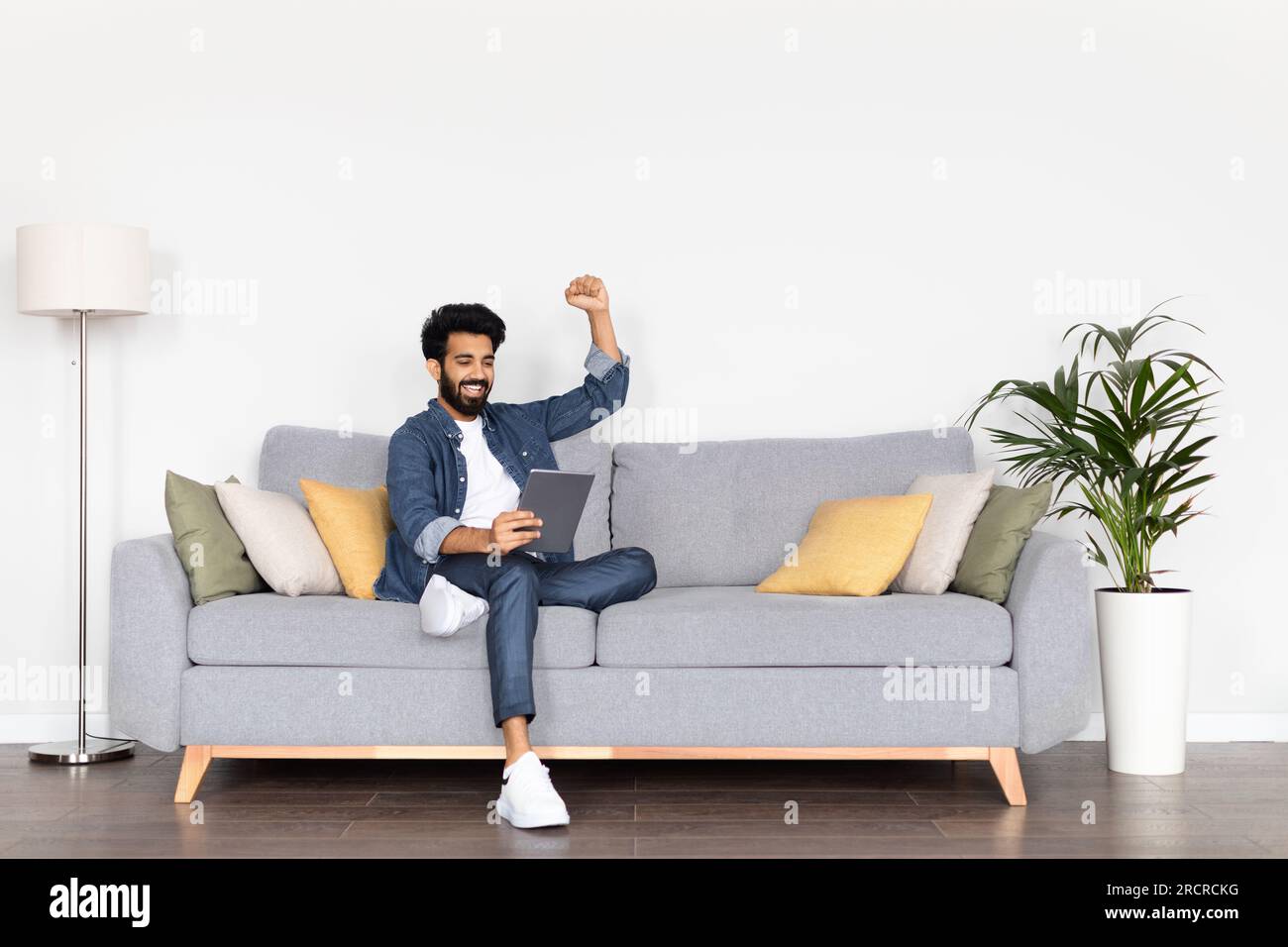 Happy arab man using digital tablet and gesturing at home Stock Photo