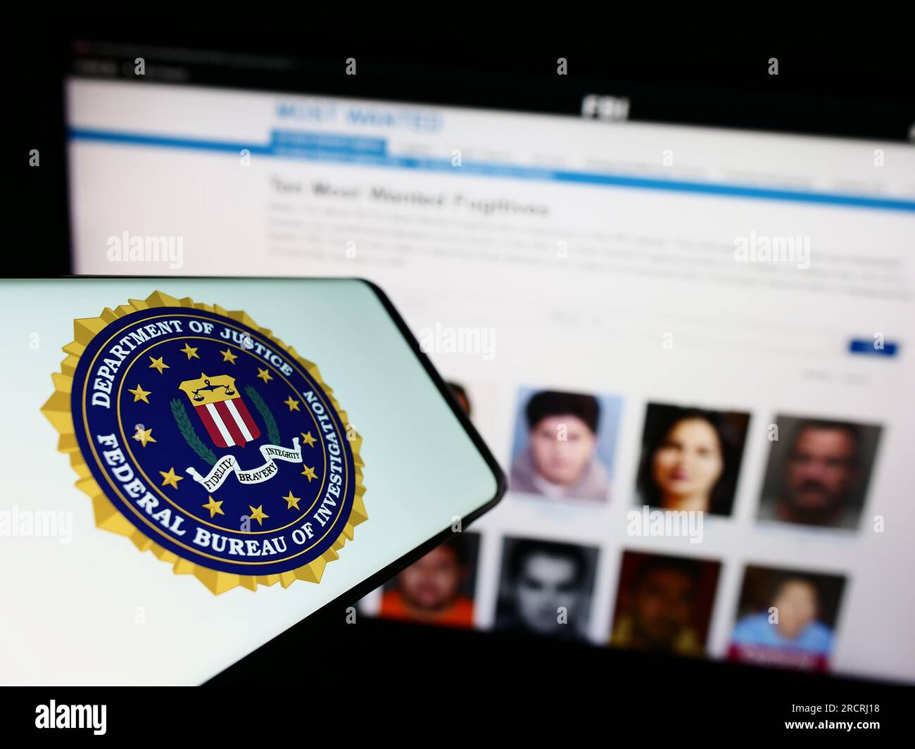 Mobile phone with seal of US Federal Bureau of Investigation (FBI) on screen in front of website. Focus on center of phone display. Stock Photo