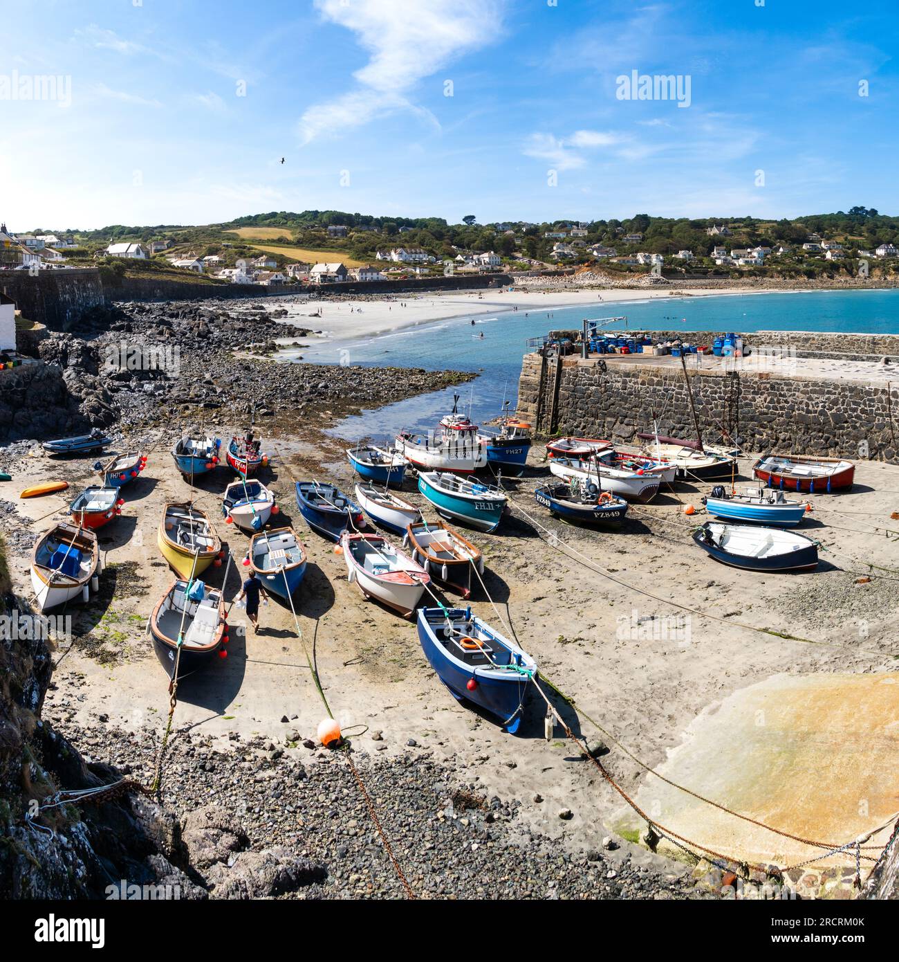 COVERACK, CORNWALL, UK - JULY 7, 2023.   Landscape view of traditional Cornish fishing boats moored in the tidal harbour of the quaint fishing village Stock Photo