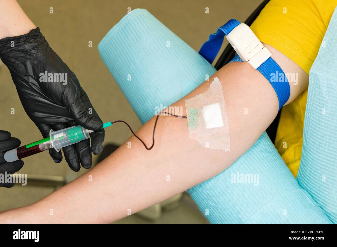 Lab technician taking blood sample from arm vein with vacutainer