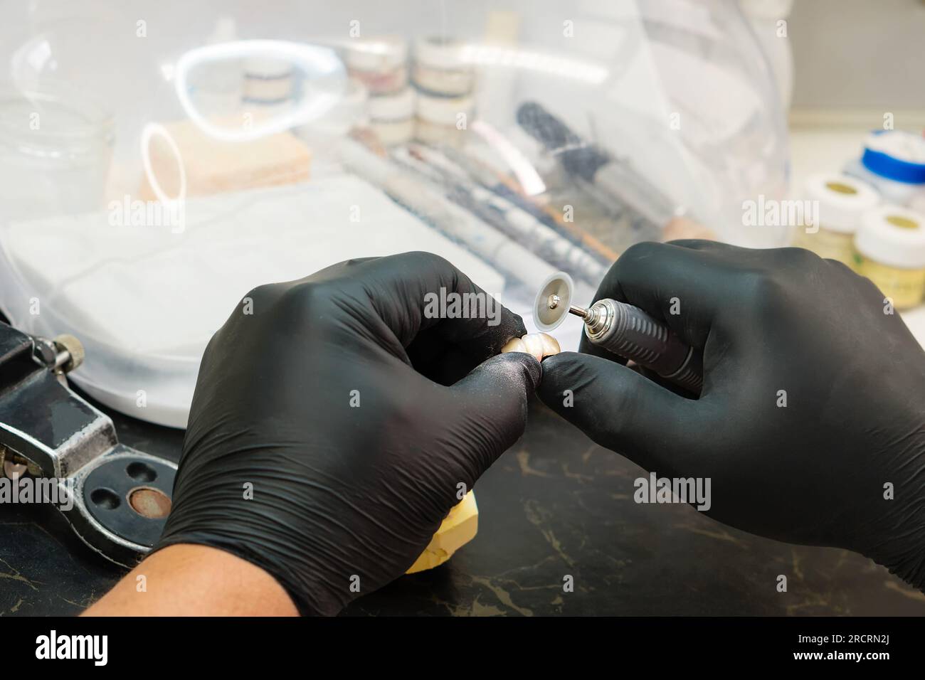 Manufacturing of dentures close up. Dental technician worker working on