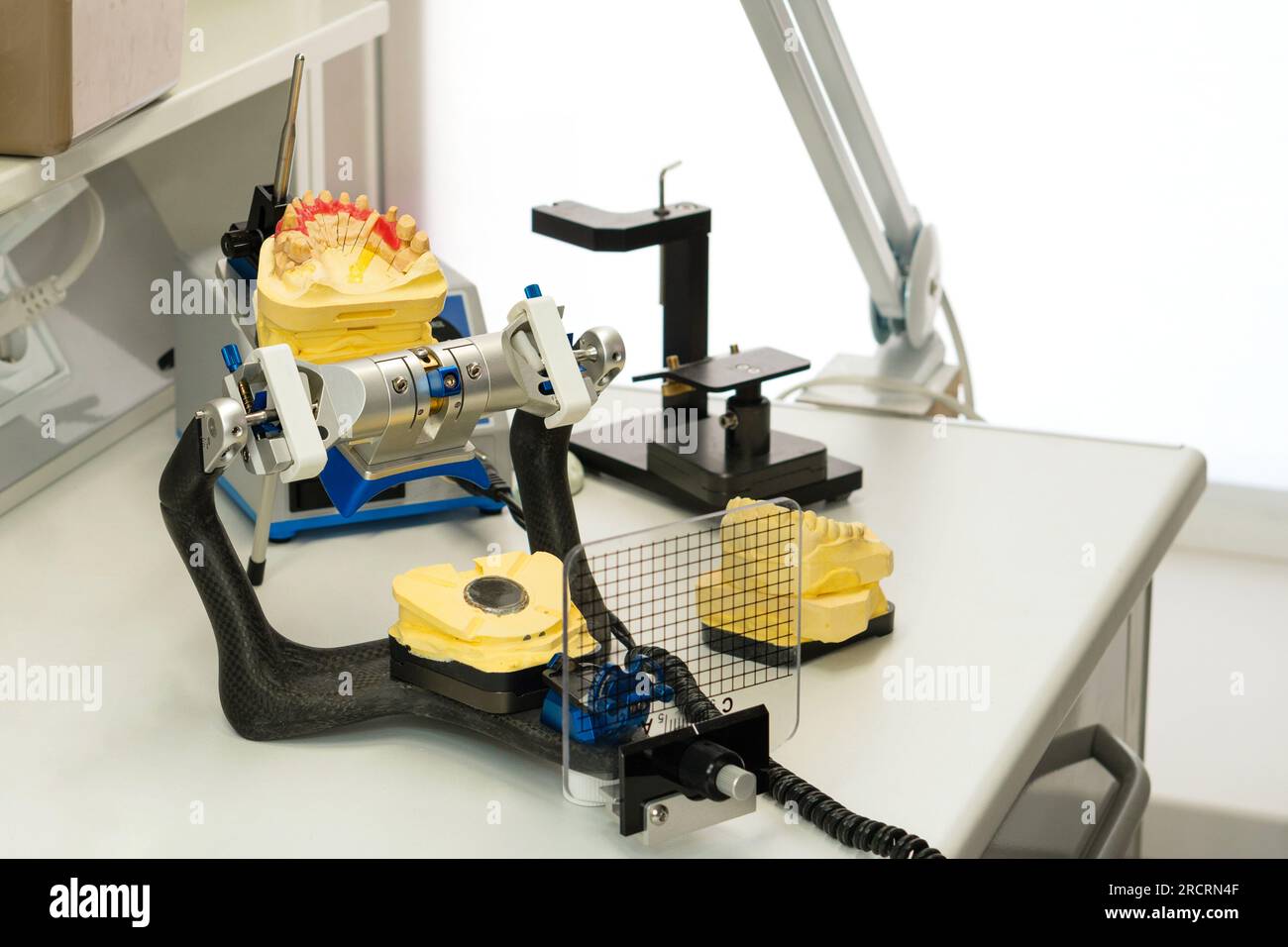 Articulator with plaster model of jaw stands on desktop of dental