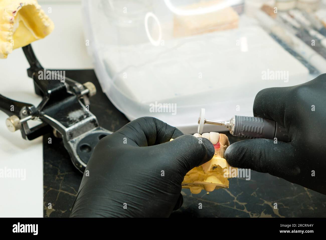 Manufacturing of dentures close up. Dental technician worker working on