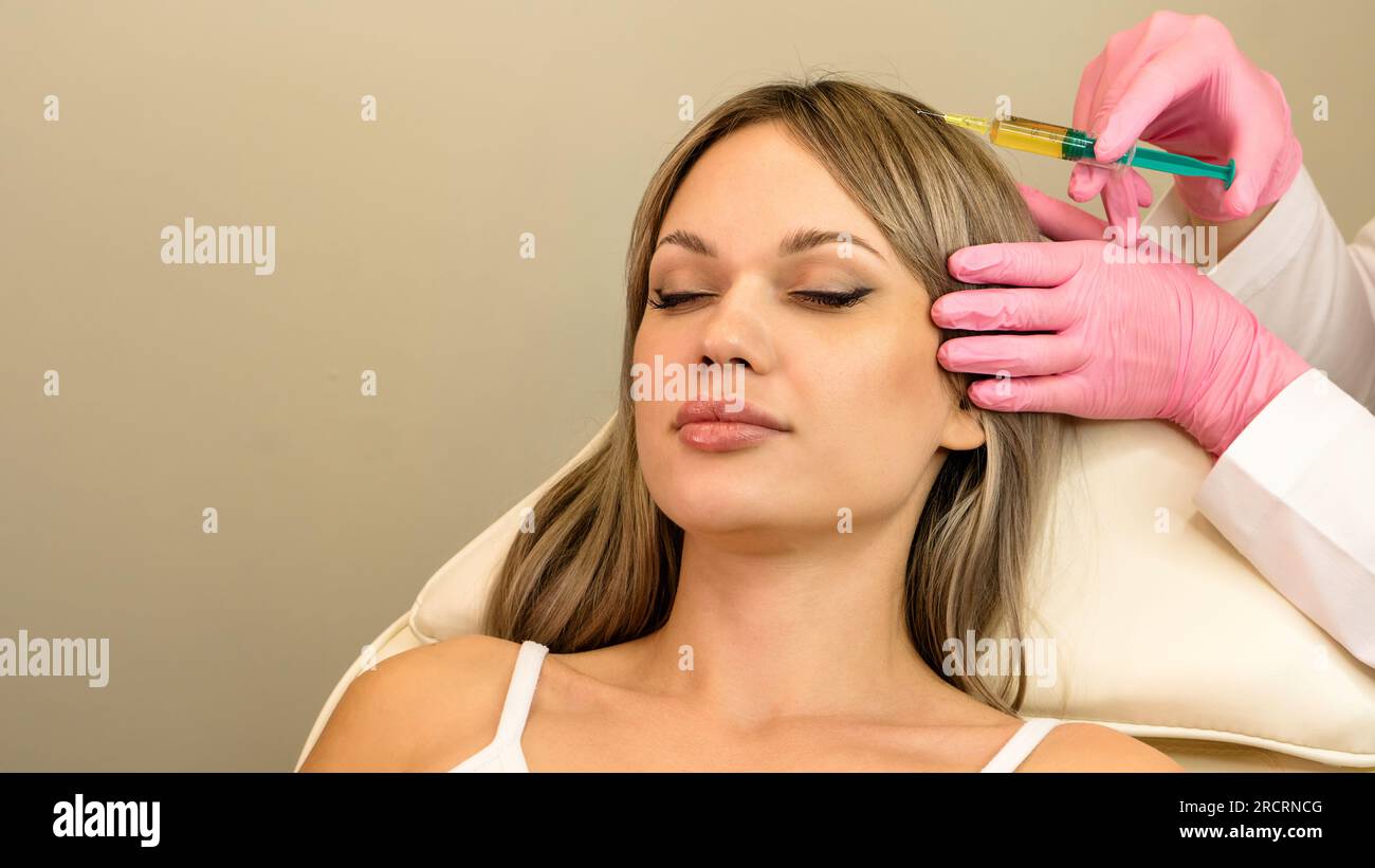 Сosmetologist uses thin needle to inject PlateletRich Plasma in scalp