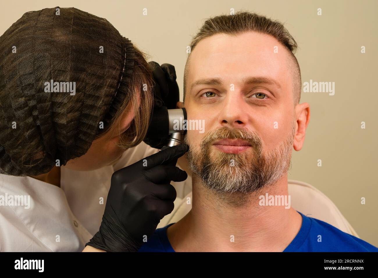 Doctor dermatologist examines moles and birthmarks of male patient with