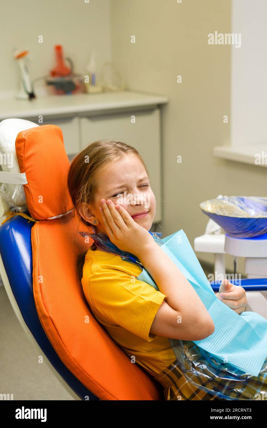 Schoolgirl experiencing severe toothache while sitting in dental chair