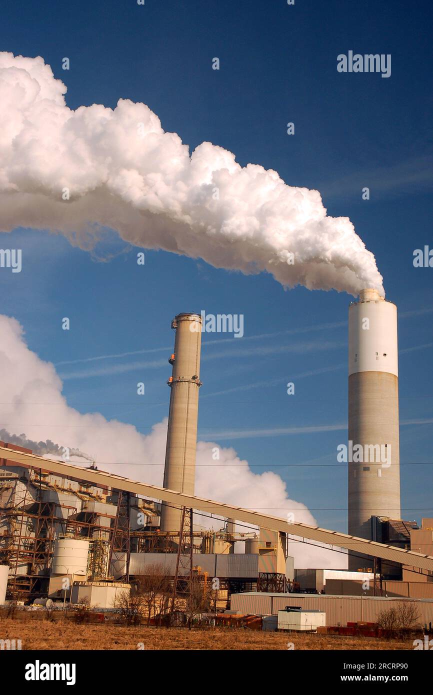 Pollution belches from a smoke stack at an industrial complex, responsible for climate change and a global warming environment Stock Photo