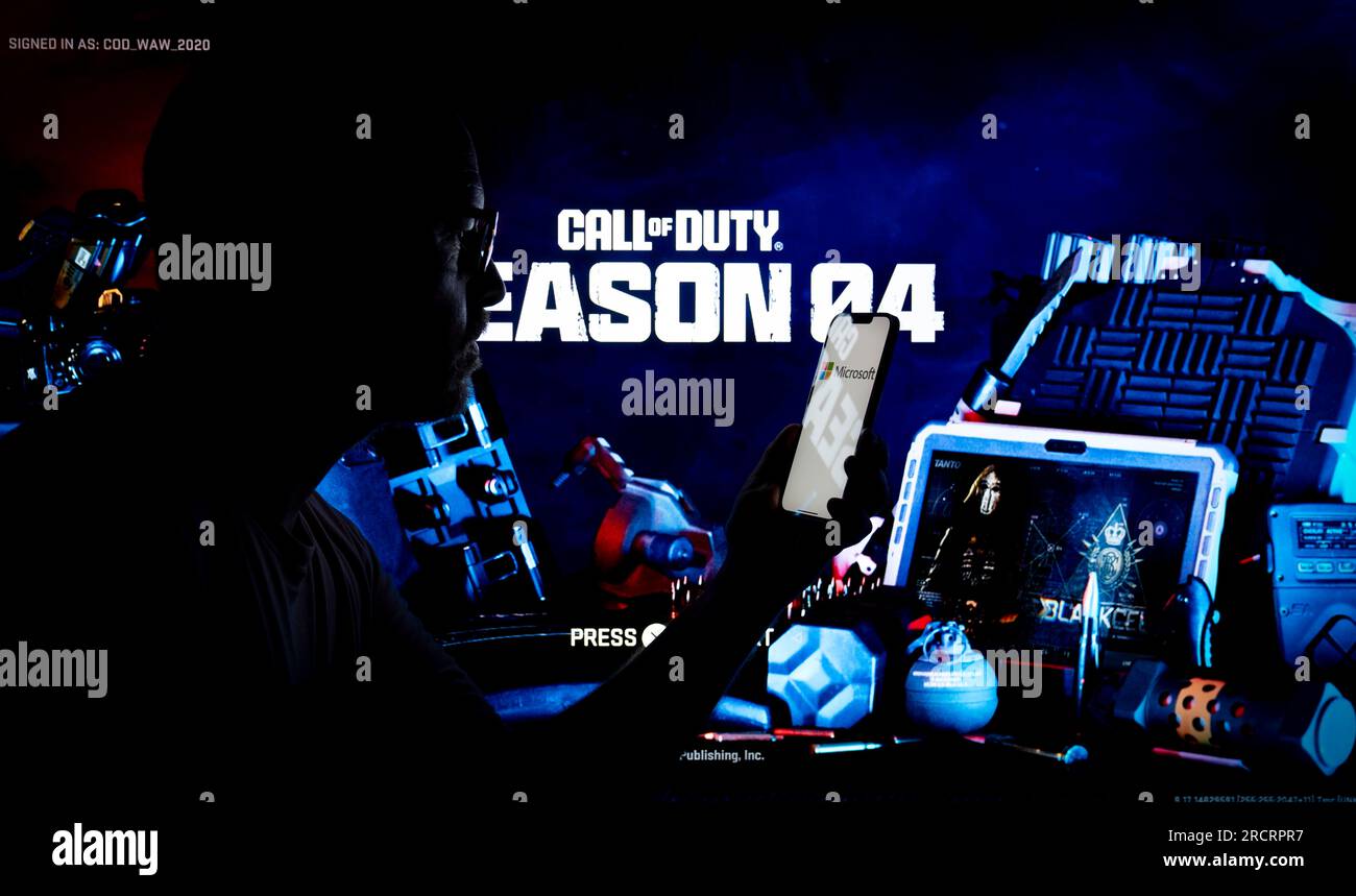 The Acitivision Call of Duty game is seen running on a Playstation console with a person holding a mobilde device in the foreground in this photo illu Stock Photo