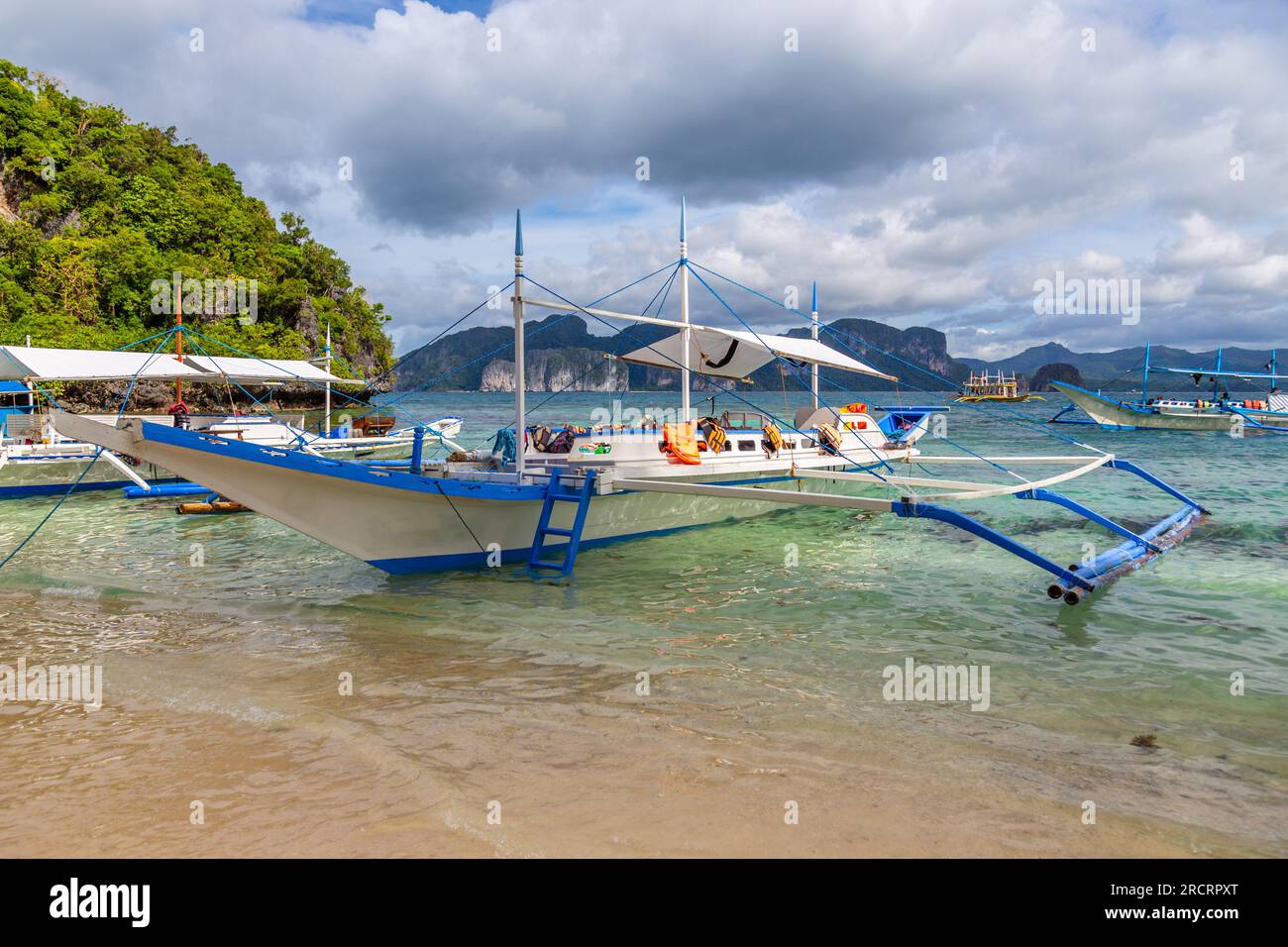 Tropical island landscape with bangca traditional phillipinians boats anchored at the shore, Palawan, Philippines Stock Photo