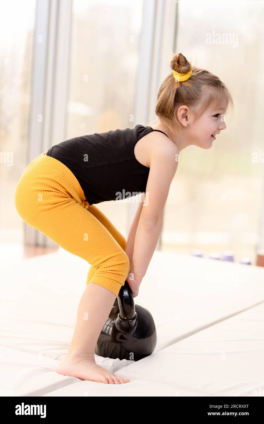 Cute little girl trying to lift kettlebell. Fitness fun Stock Photo Alamy