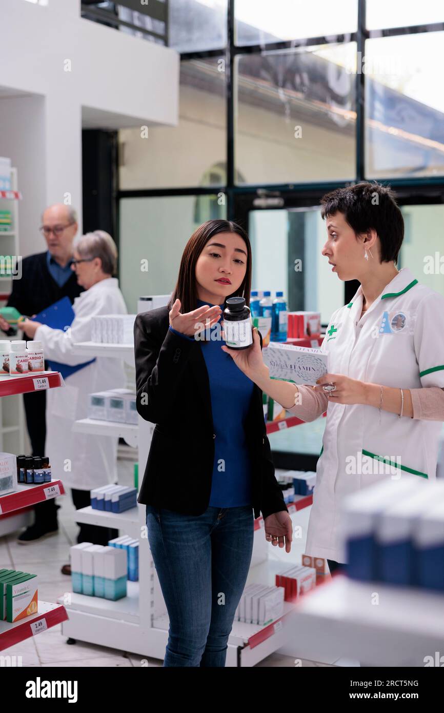 Young asian woman returning wrong vitamin package in drugstore, asking
