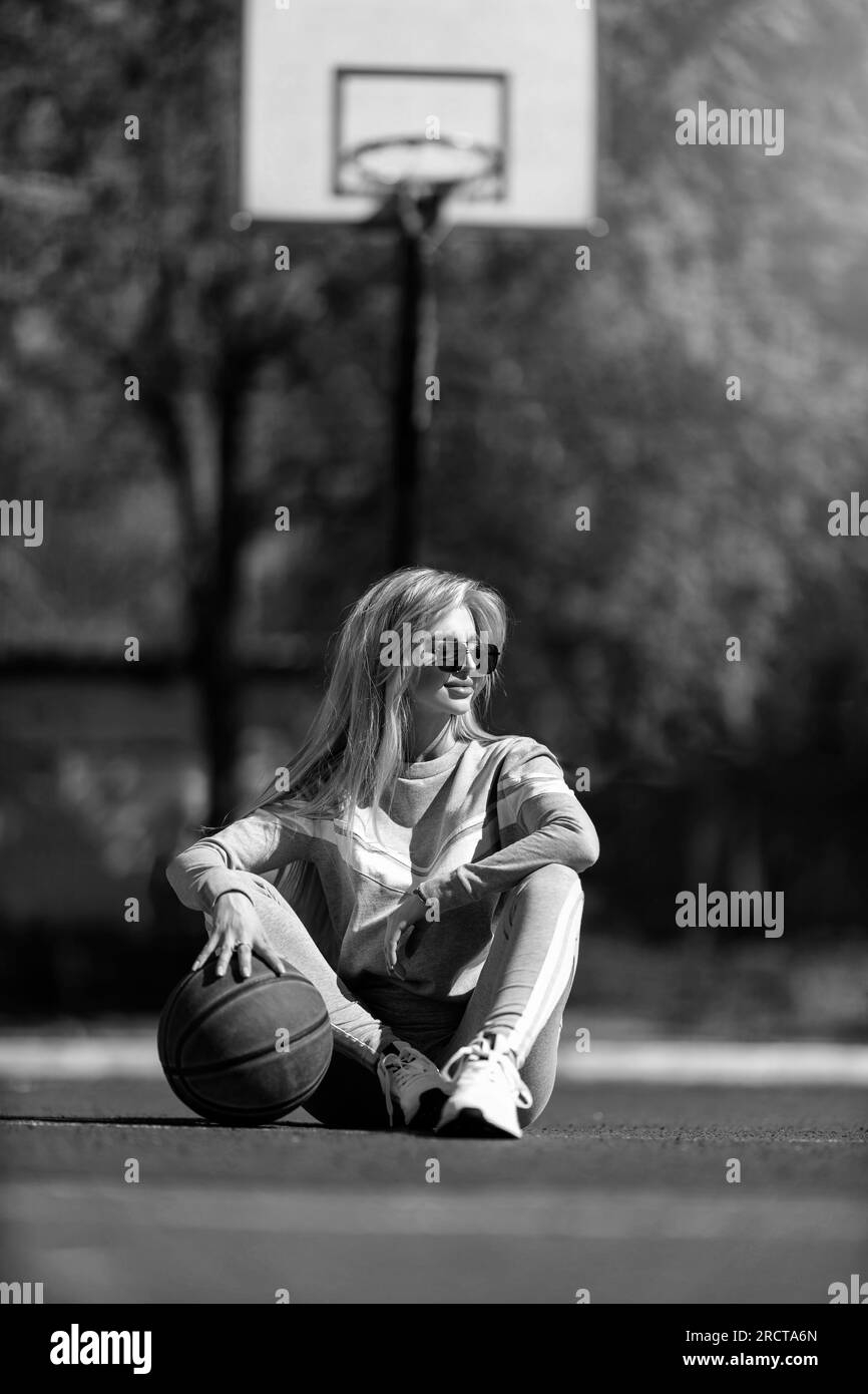 sports girl blonde sits on the basketball court black and white Stock