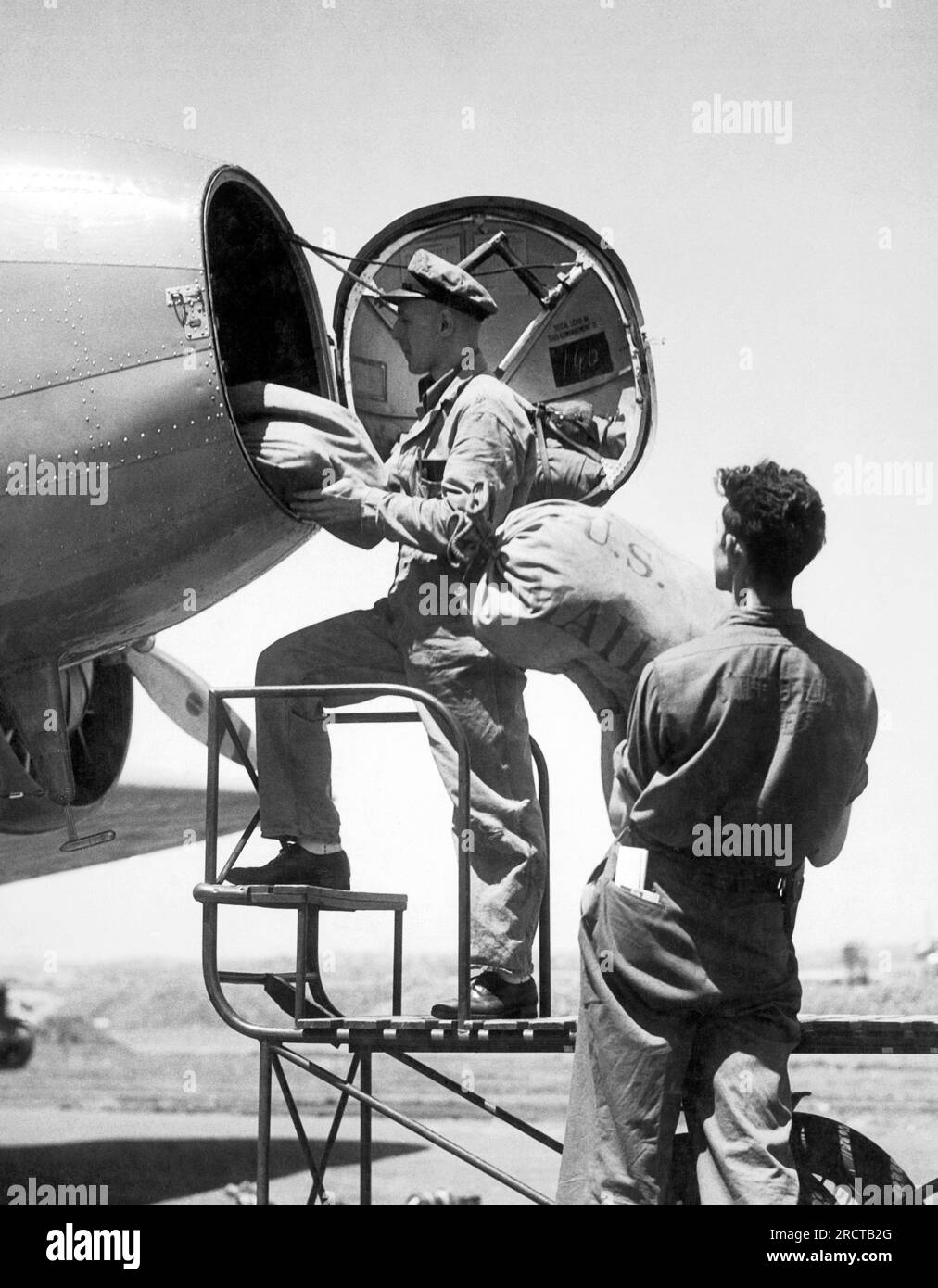 United States c. 1933 Two young men loading bags of mail into the nose