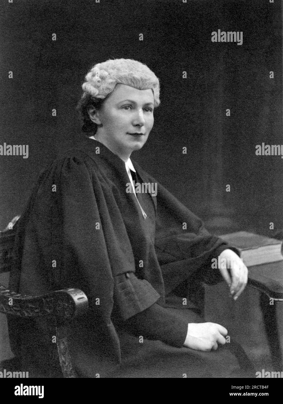London, England:  c. 1928. A portrait of a young woman judge wearing the British wig seated at a desk. Stock Photo