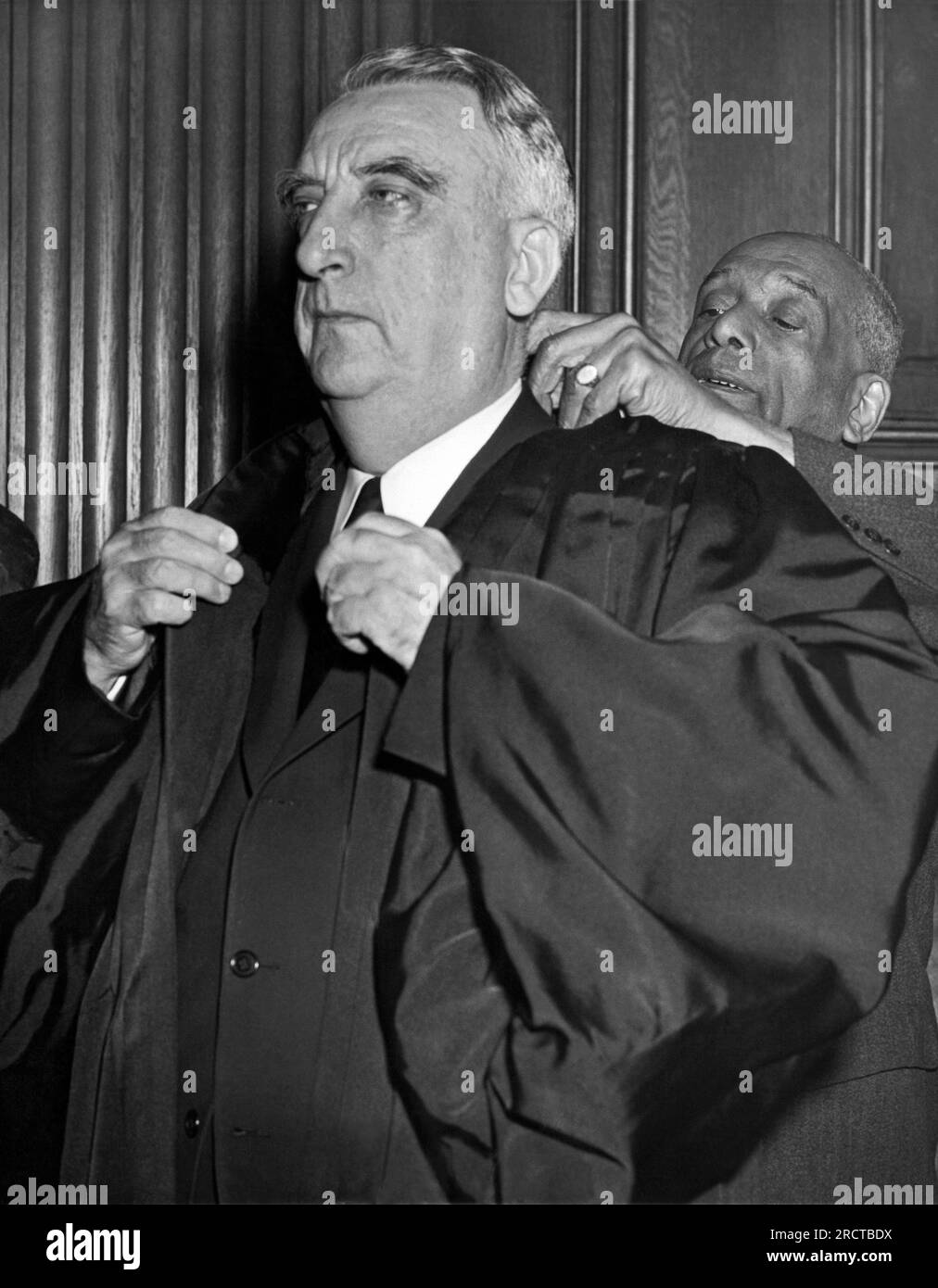 Washington, D.C.:  October 7, 1946. The new Chief Justice of the Supreme Court, Fred Vinson, is helped from his robes by attendant Robert Marshall after completing his first day as presiding judge of the nation's highest court. Stock Photo