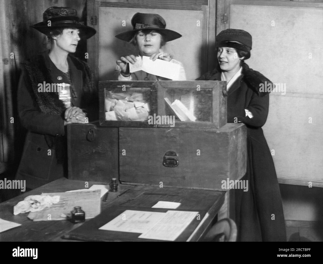 New York, New York:  c. 1917 Three suffragists casting votes in New York City. The original caption read: 'Calm about it. At Fifty-sixth and Lexington Avenue, the women voters showed no ignorance or trepidation, but cast their ballots in a businesslike way that bespoke study of suffrage.' Stock Photo