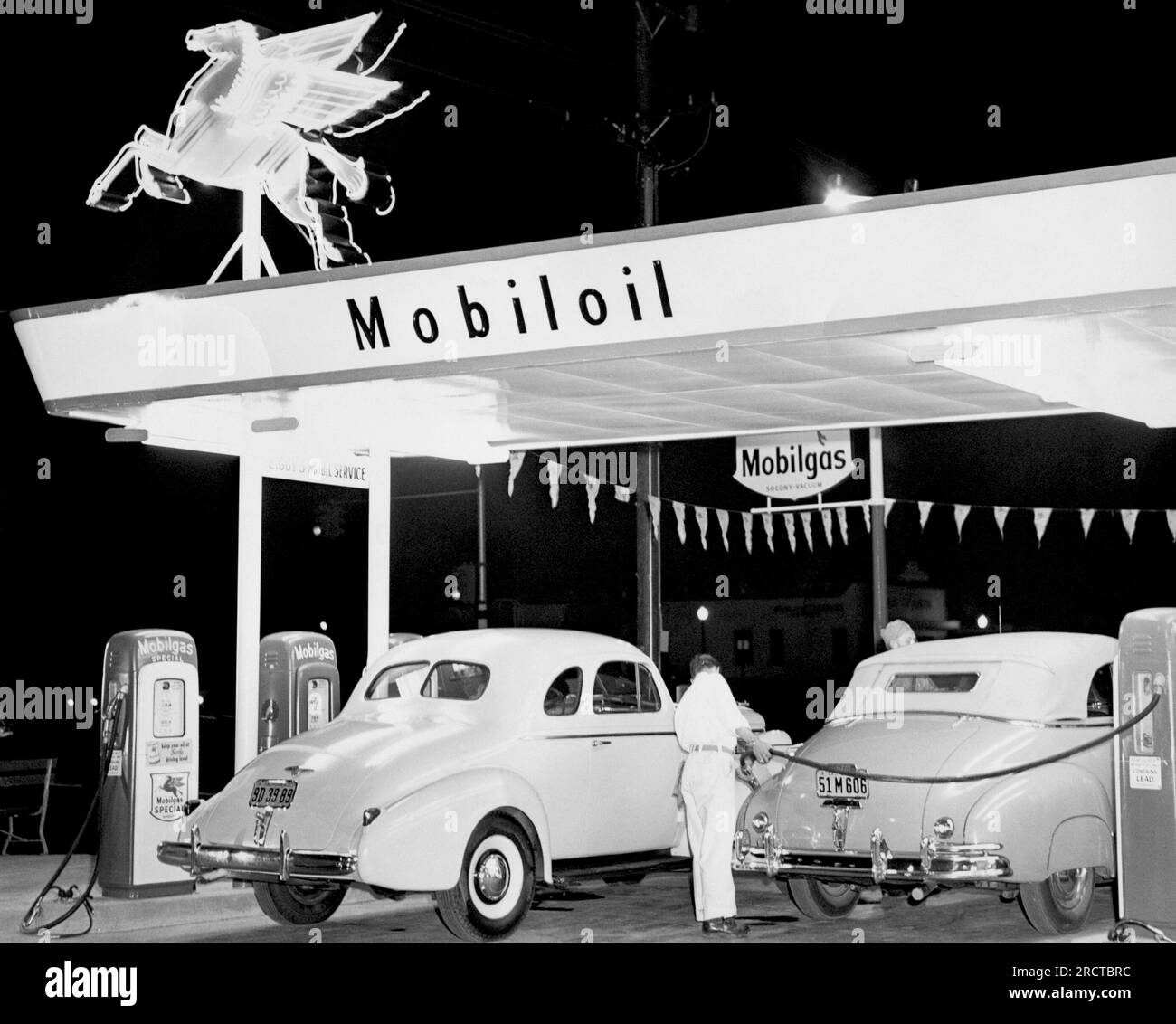 California:  c. 1939 A rear view of a Mobil gas station attendent filling a car with fuel. Stock Photo