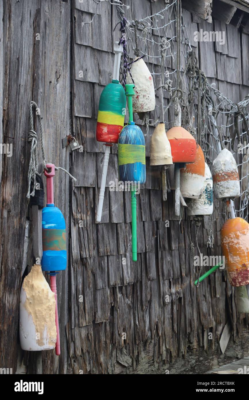 colorful buoys and netting hanging on a weathered wood wall of a shack Stock Photo