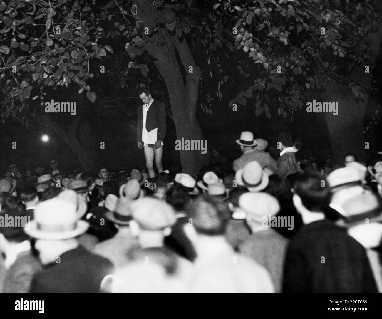 San Jose, California:   November 27, 1933. The body of Thomas Thurmond, alleged kidnaper and slayer of Brooke Hart, shown after a mob which dragged him from the county jail, completed its work. He was beaten and hanged from a tree in St. James city park, 100 yards from the jail. John Holmes, his alleged accomplice, was strung up a few minutes later. Stock Photo