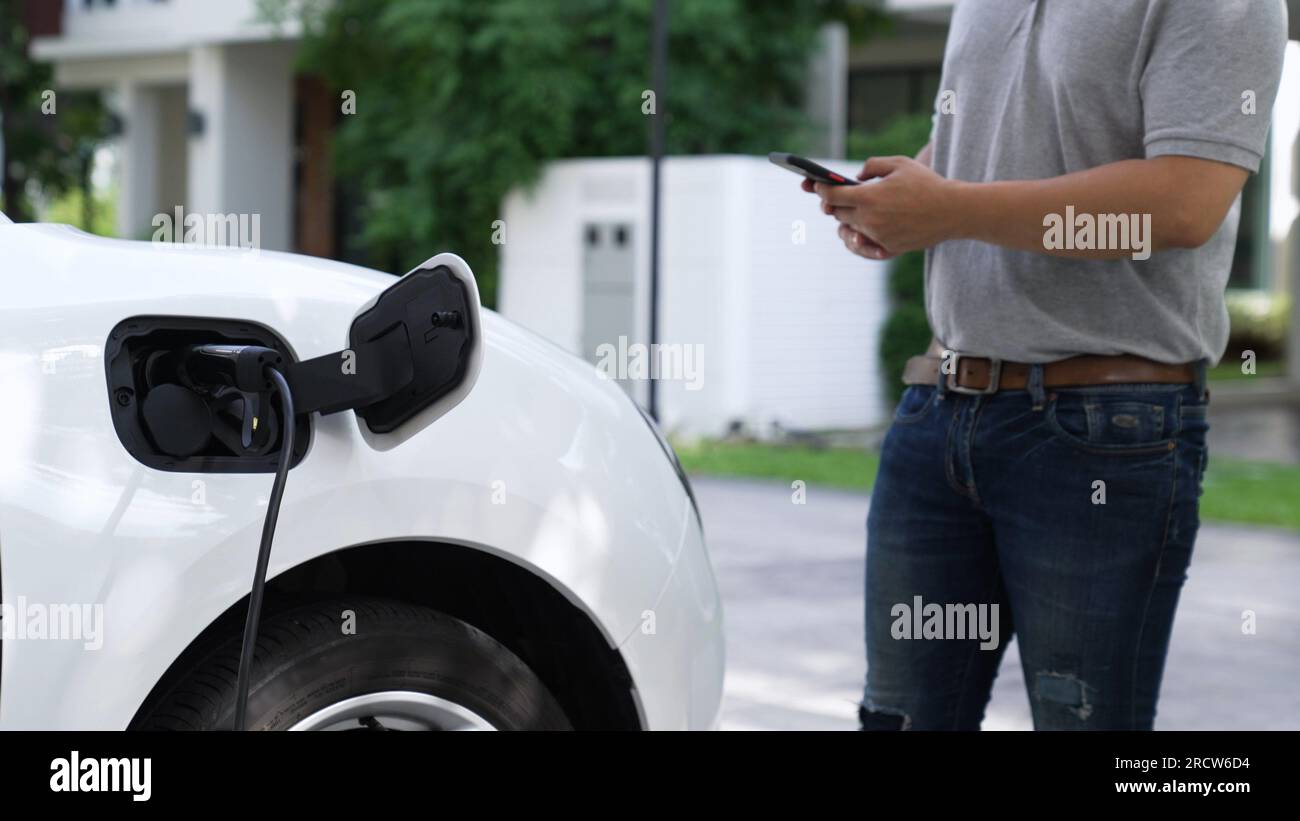 Electric car plug into home charging station to recharge battery with electricity by EV charger