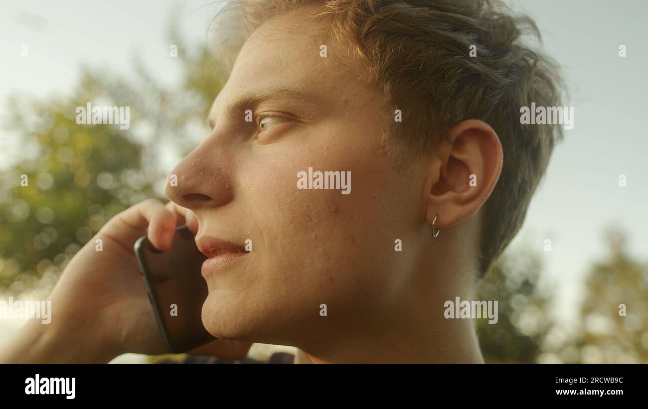 Handsome Blond Young Man Answering a Phone Call and Engaging in Conversation Stock Photo