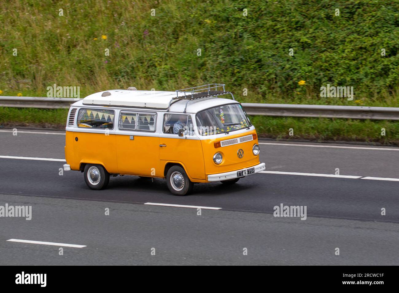 1977 70s seventies Volkswagen Motor Caravan Yellow LCV Petrol 1584 cc travelling at speed on the M6 motorway in Greater Manchester, UK Stock Photo