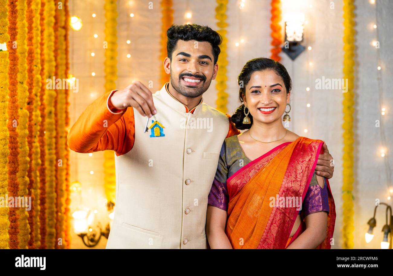 Happy young indian couple showing new home keys by looking at camera ...