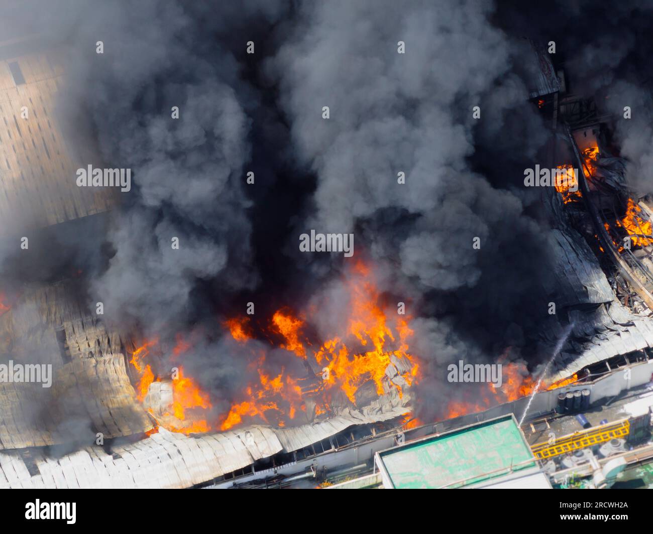 Aerial view of Fire in industrial building. Multi-storey concrete hangar with flames. Factory emergency concept. Stock Photo