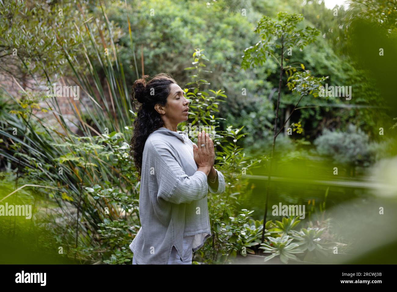 Biracial woman doing yoga, meditating in garden Stock Photo