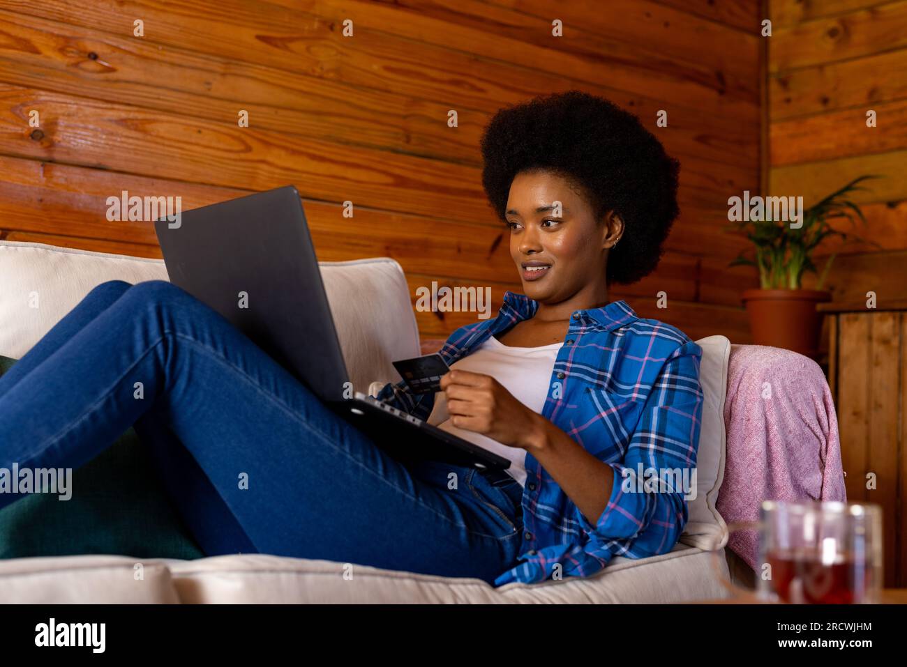 Happy african american woman relaxing on sofa in living room using ...