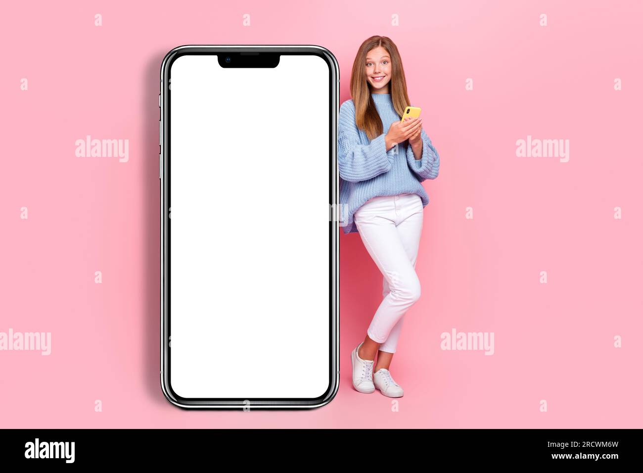 Full length size photo of positive teenager girl wear blue knitted jumper hold phone browsing phone empty space isolated on pink color background Stock Photo