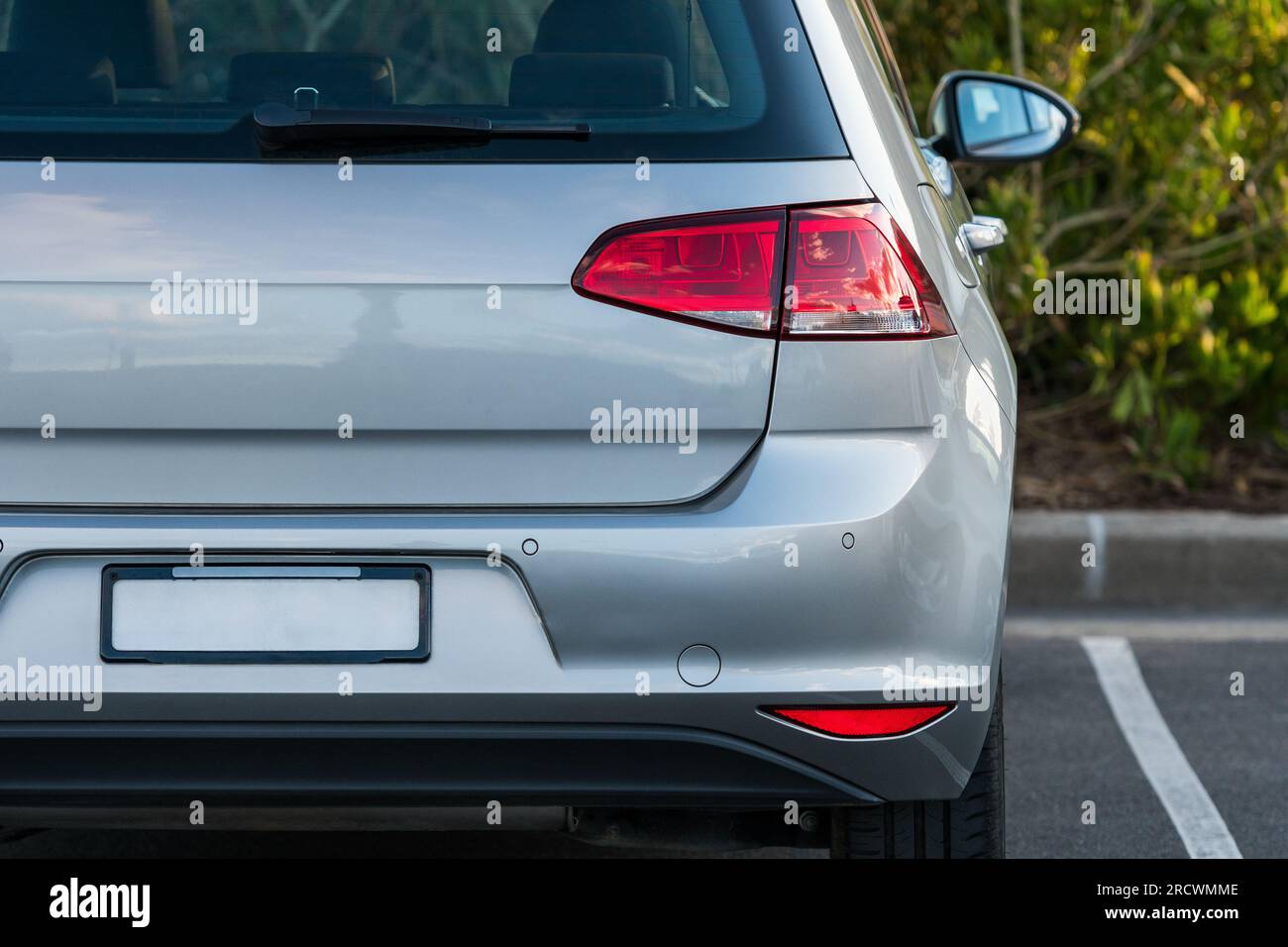 Back bumper and back lights of silver car parked on the street in summer sunny day, rear view. Stock Photo