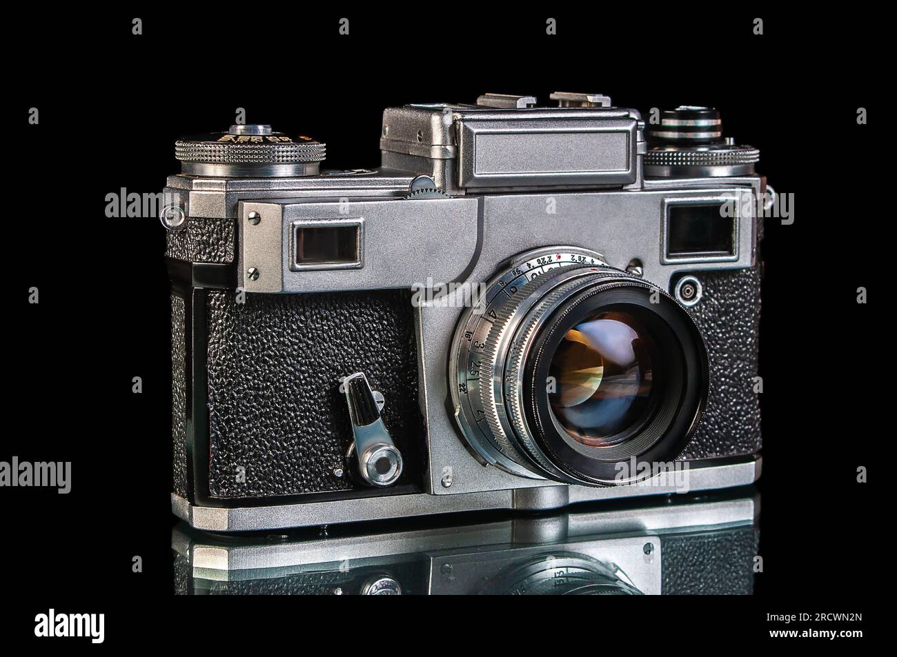 An old 35mm analog camera with a lens attached to it Stock Photo