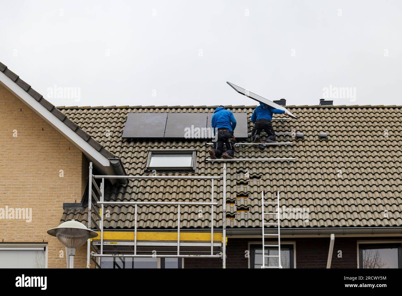 Barendrecht, the Netherlands - 2020-12-03: Two technicians installing photovoltaic panels on the roof of a home Stock Photo