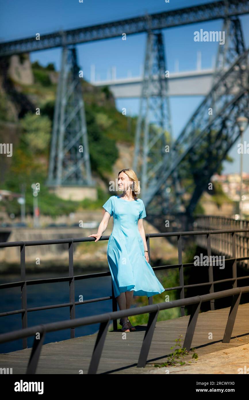 On a city promenade stands a woman in a blue dress Stock Photo - Alamy