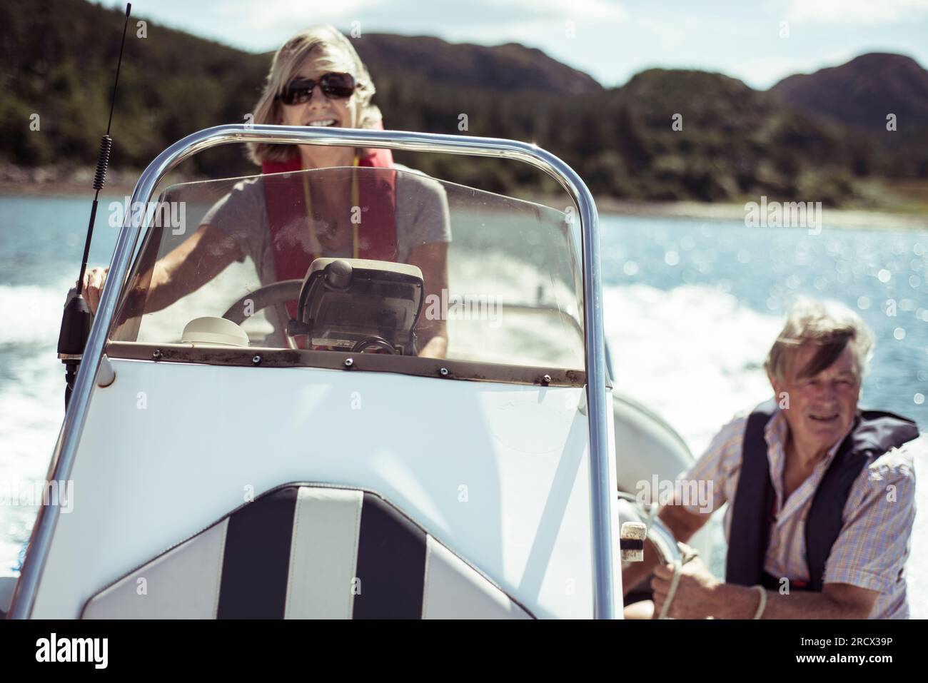 Retired couple laugh on speed boat in the sun Stock Photo