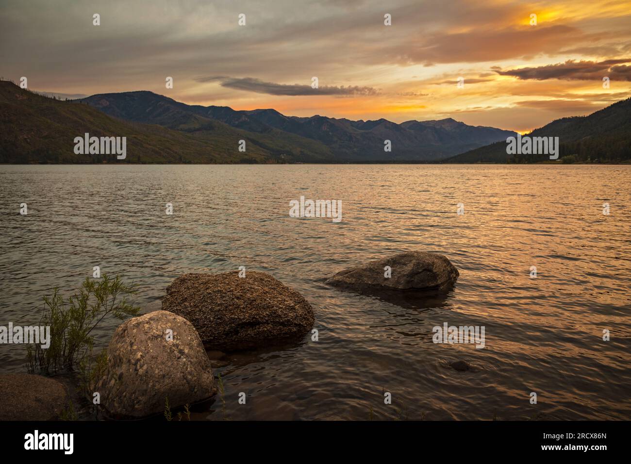 A pretty mountain lake with boulders in the foreground. Stock Photo