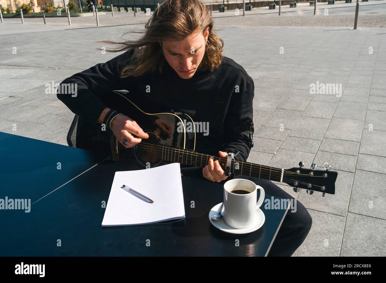 man composing music playing the guitar and reading Stock Photo