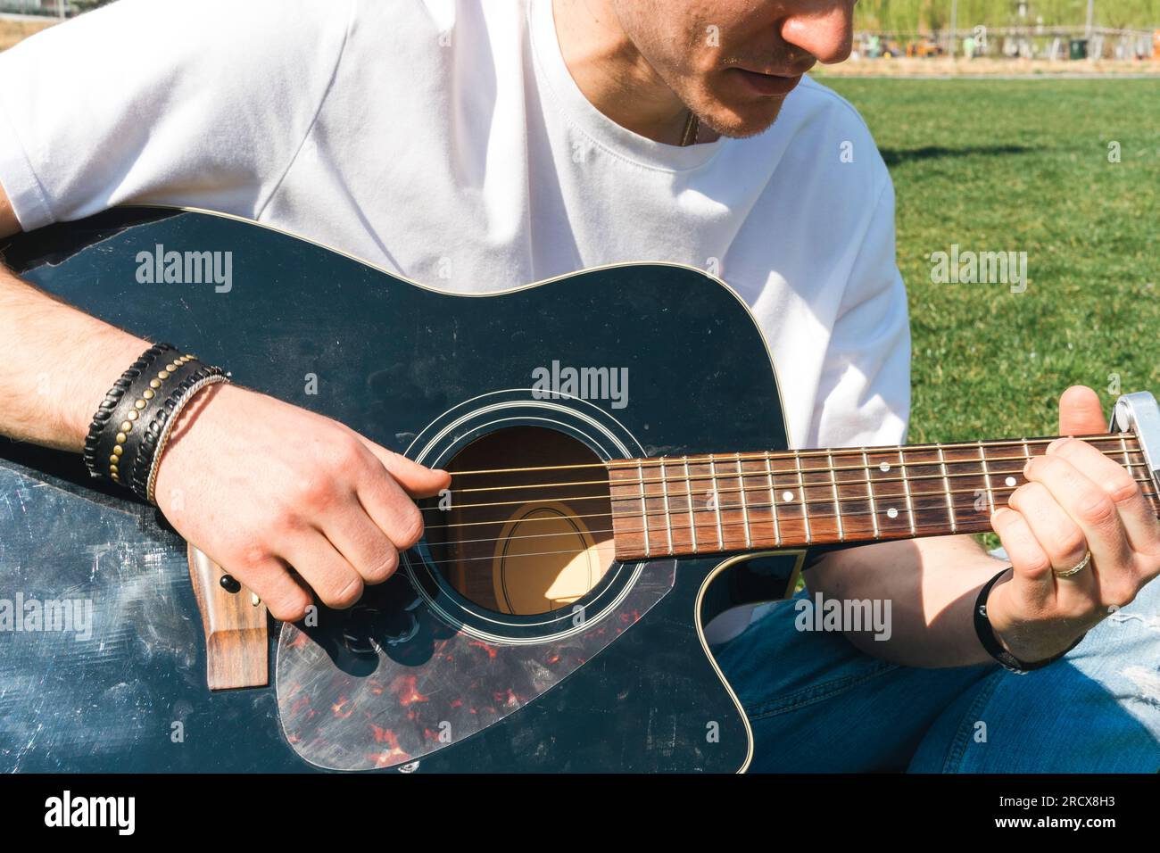 close up of a singer playing guitar in a garden during a sunny day Stock Photo