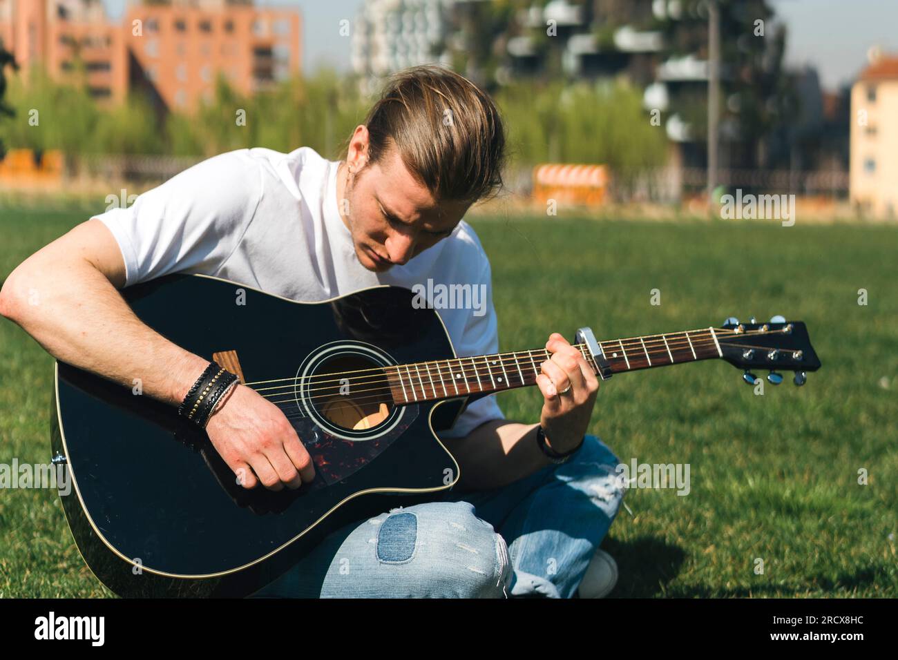 Young singer play the guitar in a garden during a sunny day Stock Photo