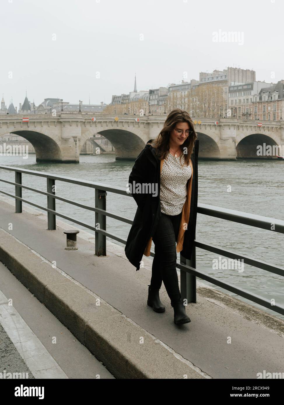 American woman walks along the Seine River in Paris Stock Photo