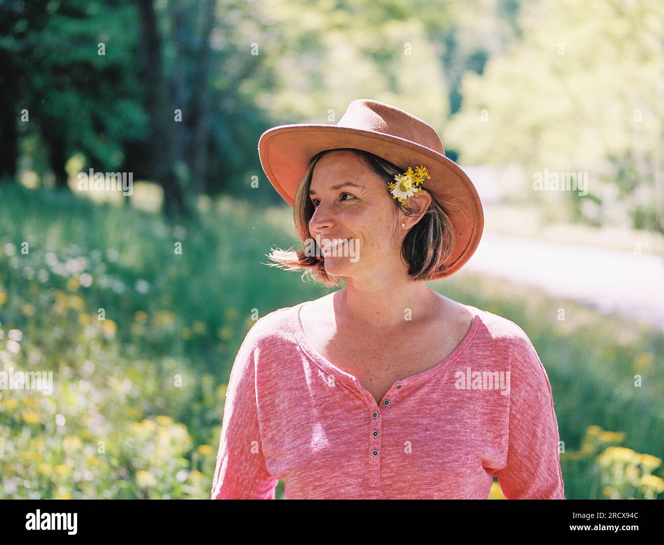 middle-aged woman in a brown hat, wildflowers tucked behind her ear Stock Photo