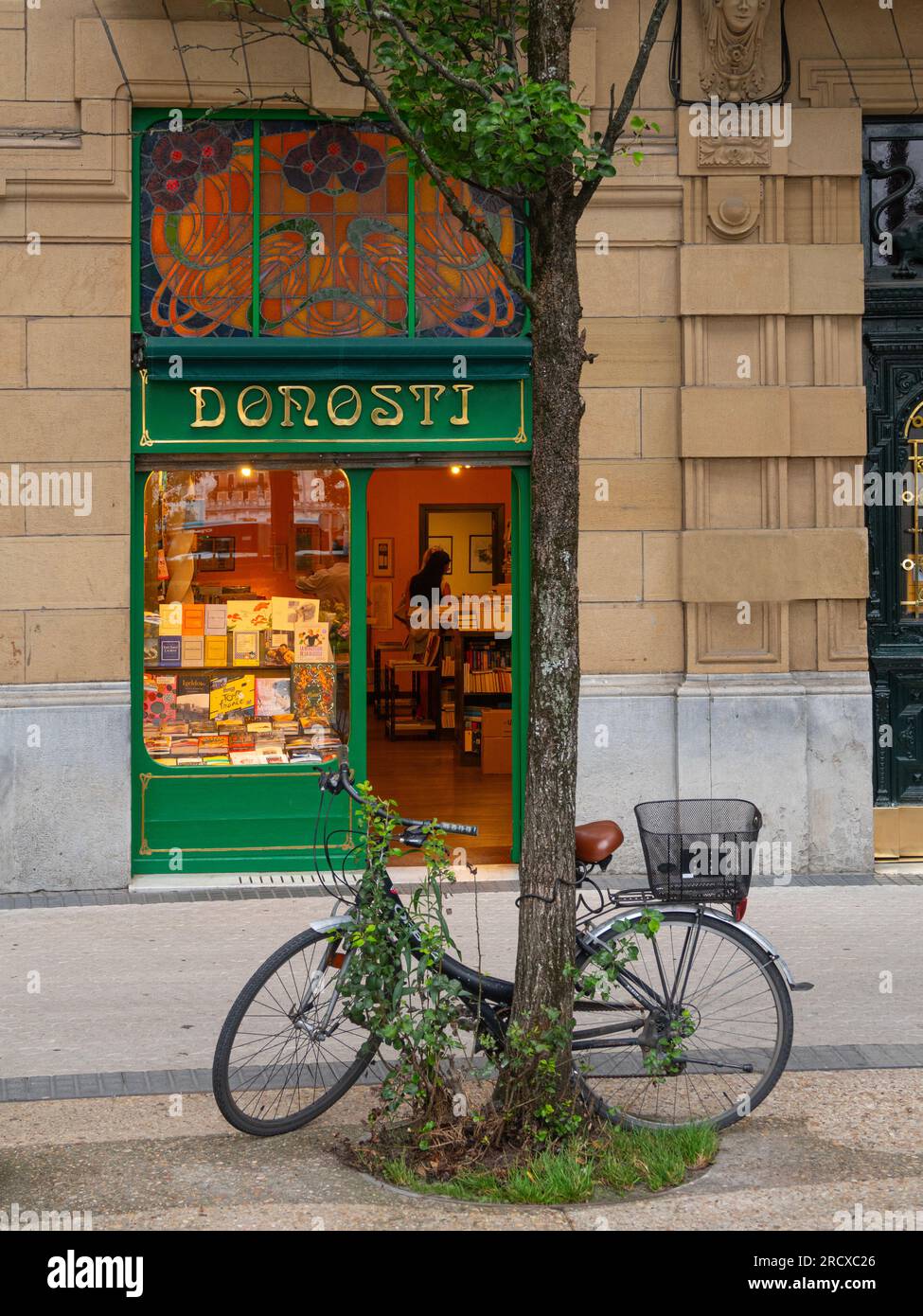 Famous Donosti bookstore in Bilbao Square with the beautiful Art Deco facade with stained glass and a bicycle parked in front of the shop. San Sebasti Stock Photo