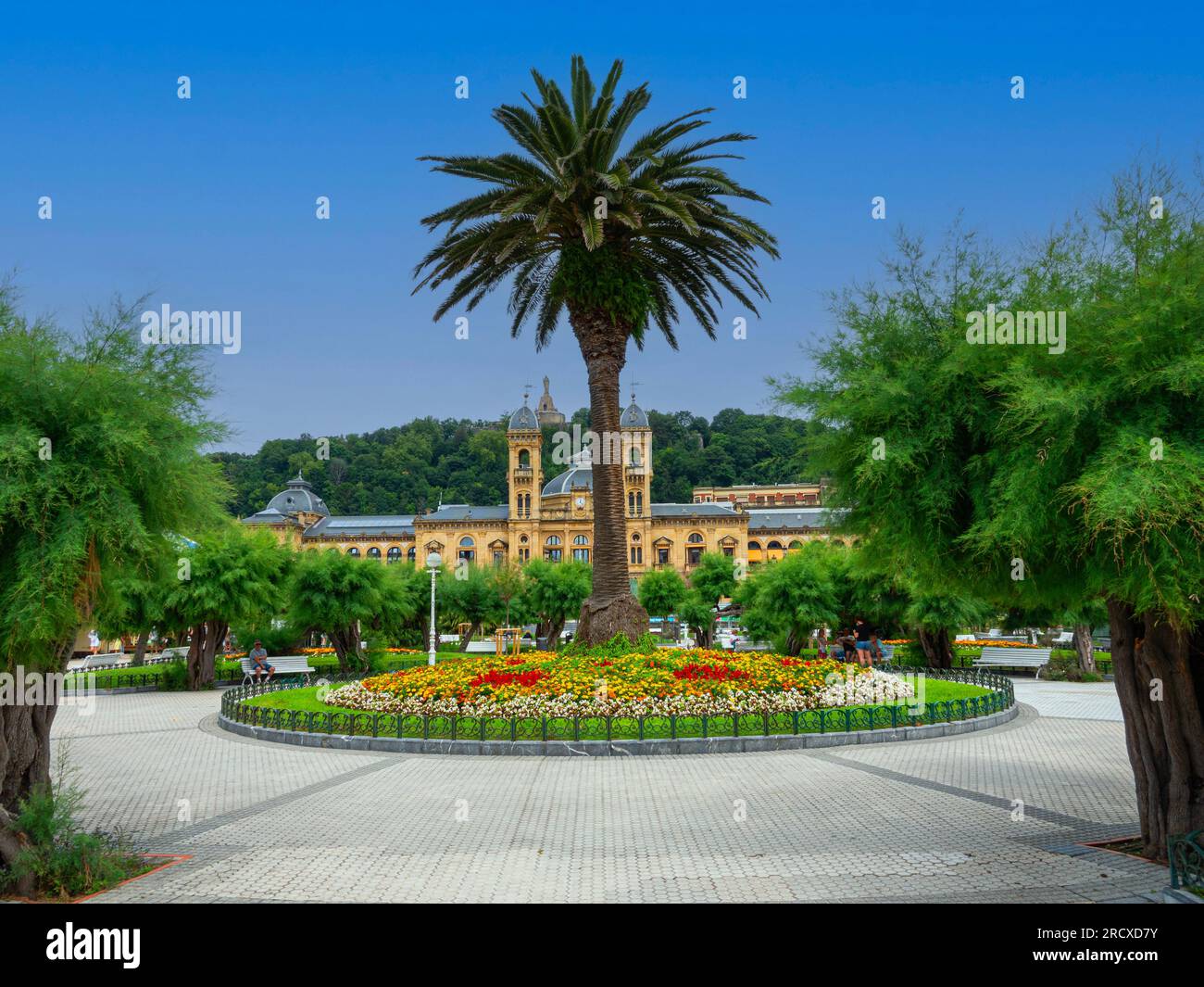 Alderdi Eder Gardens in San Sebastian, Spain, palm and tree–filled park by the beach, with colorful gardens. In the background the old city hall and c Stock Photo
