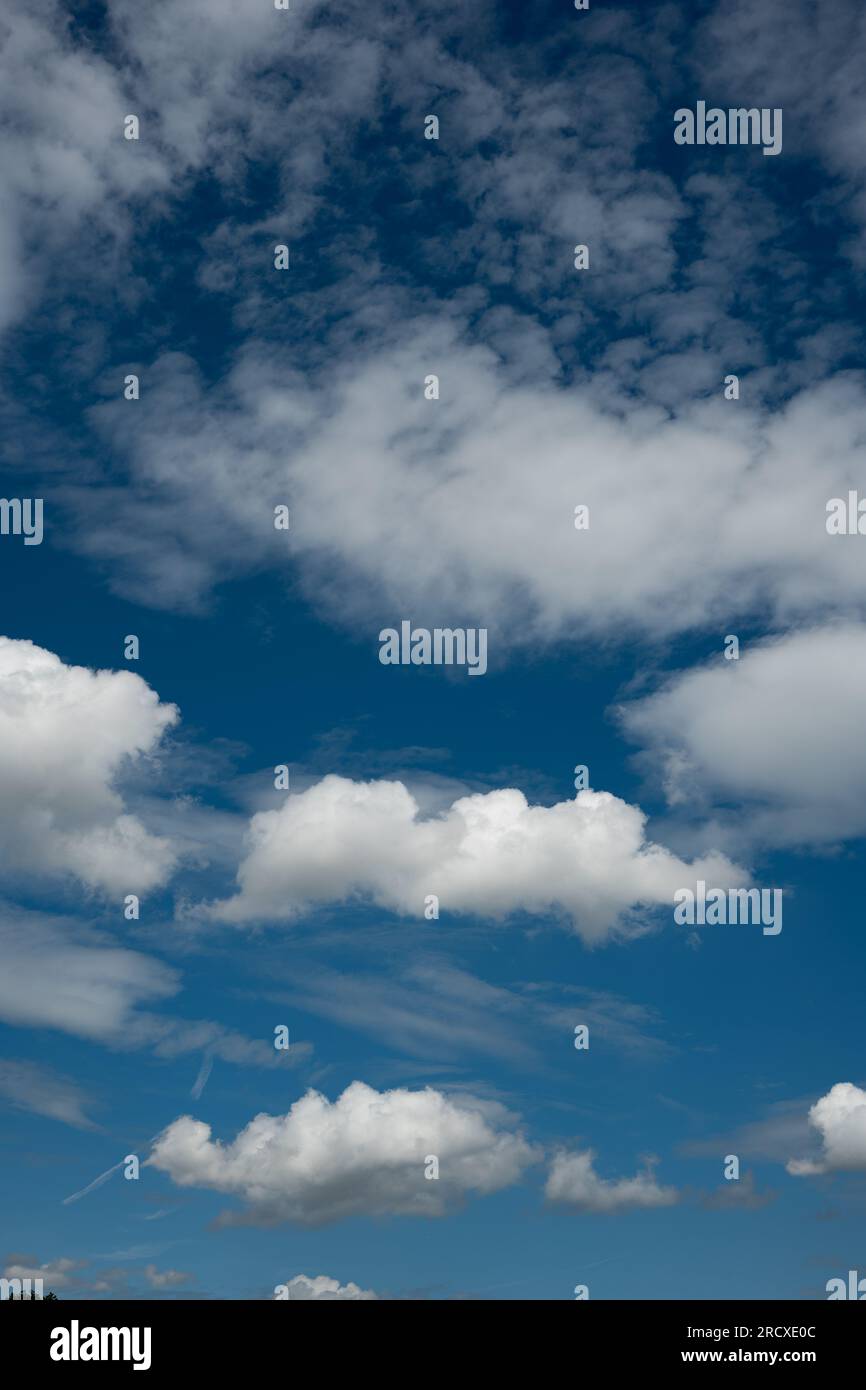 White puffy clouds set against a deep blue summer sky Stock Photo